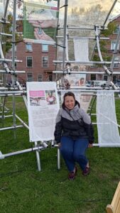 Een foto van Nathalie in het park. Ze zit voor posters met stukken tekst