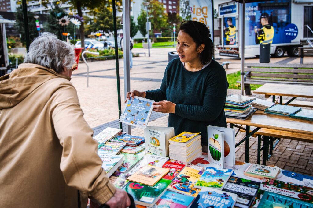 Een foto van Nathalie Cheu-Choi die een boek aanbied aan een klant