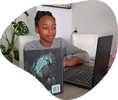 Een foto van een kind dat achter haar laptop zit met daarnaast een leesboek